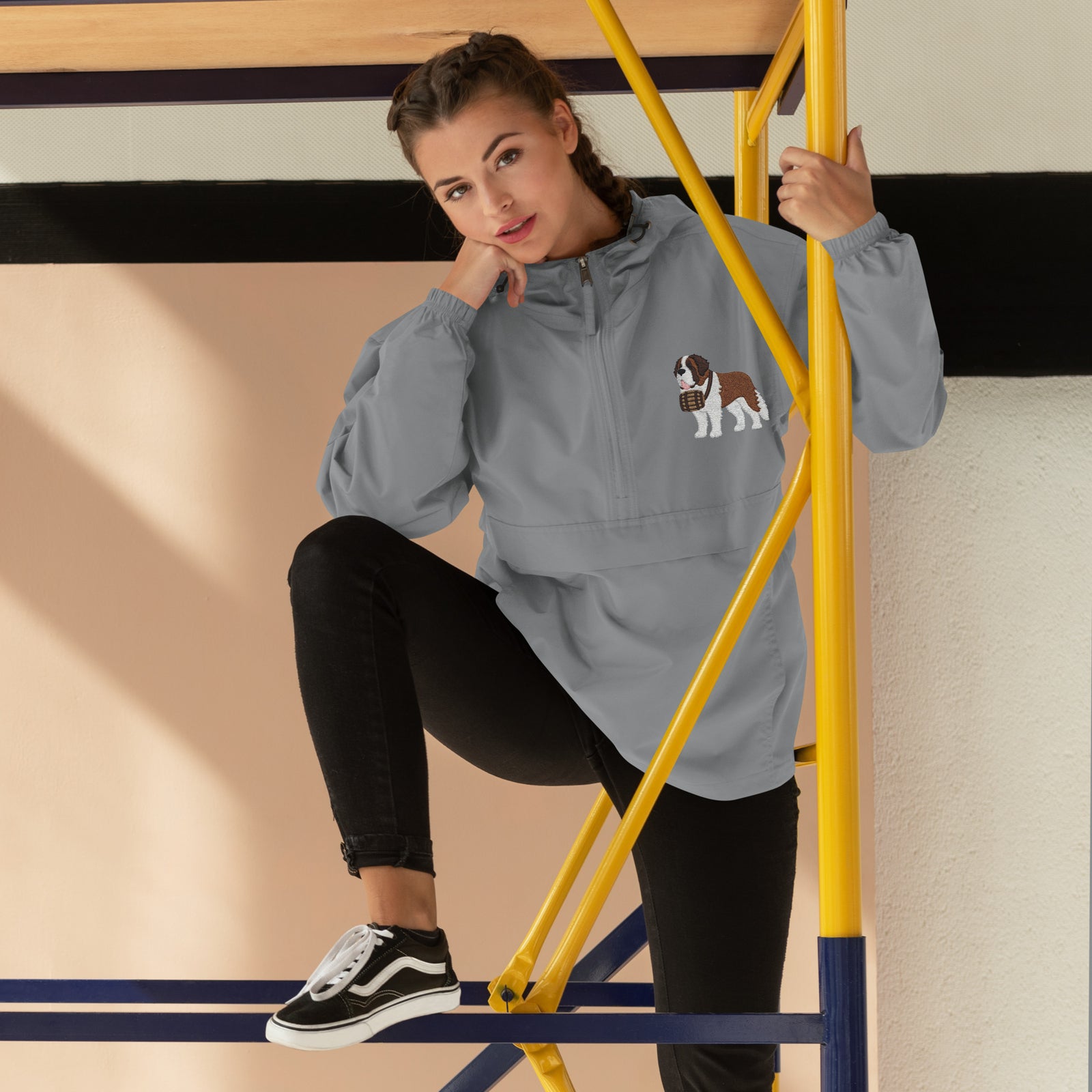 Light gray Champion packable windbreaker with chest embroidered Saint Bernard and barrel, half zip pullover with hood, kangaroo pocket, and zip pouch.