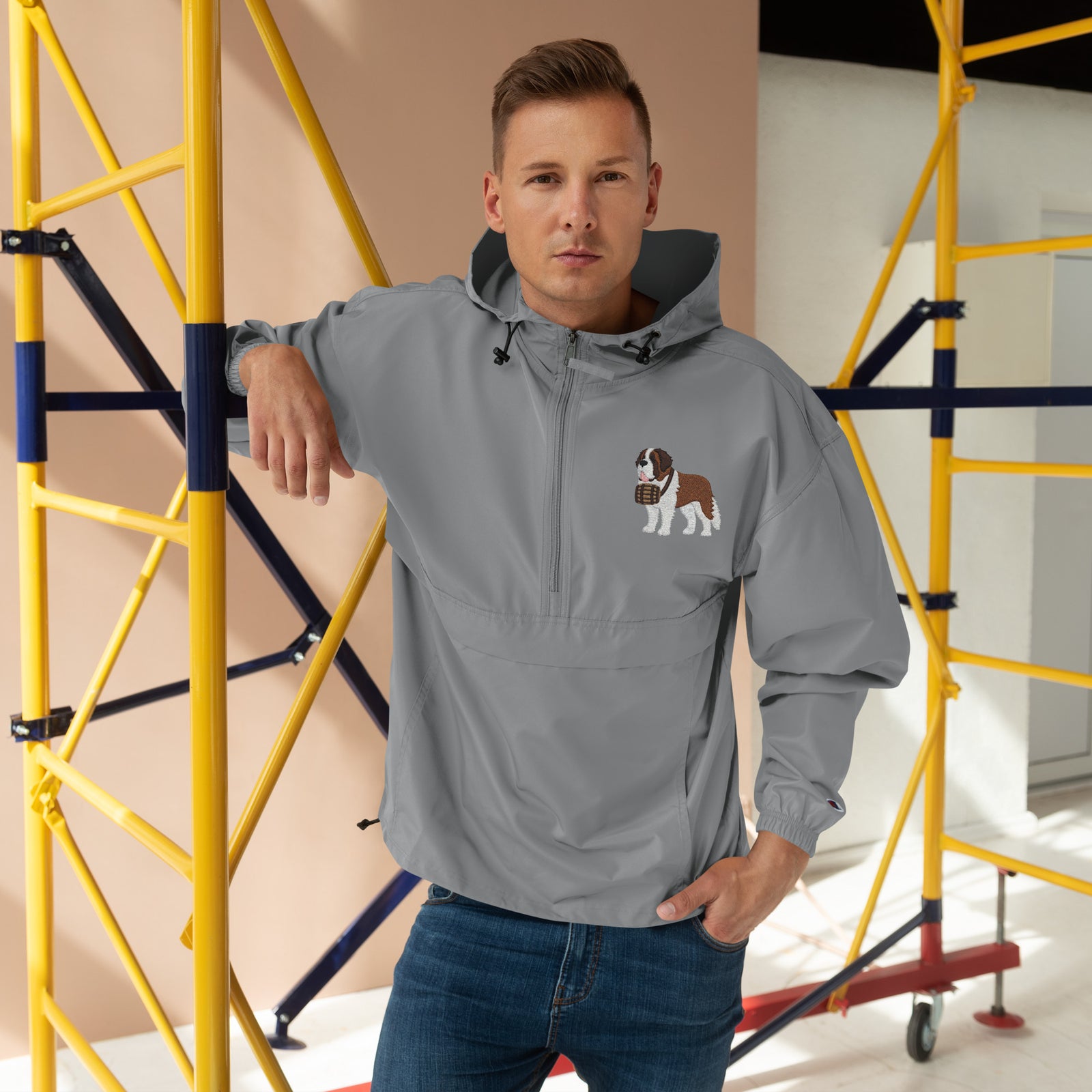 Light gray Champion packable windbreaker with chest embroidered Saint Bernard and barrel, half zip pullover with hood, kangaroo pocket, and zip pouch.