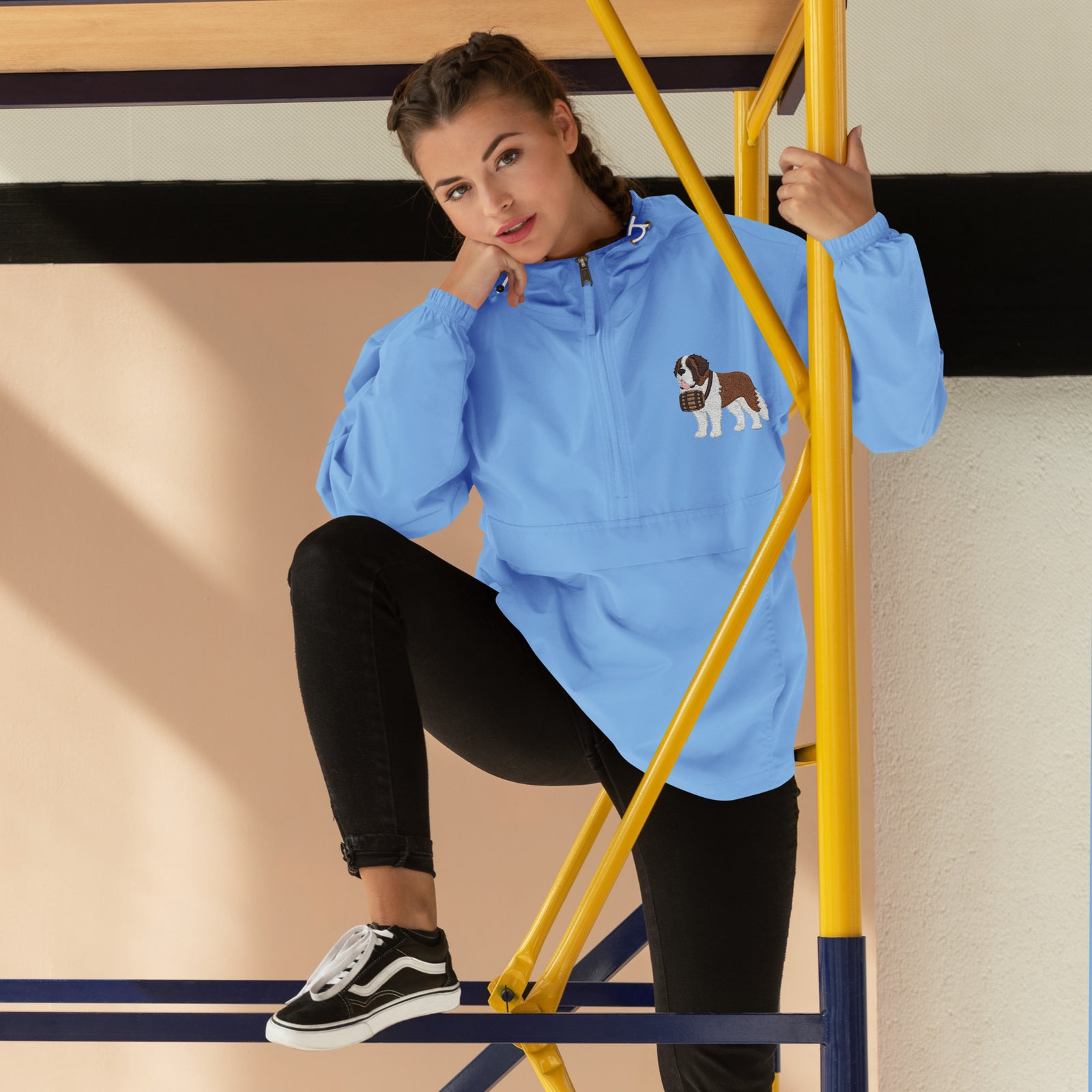 Light blue Champion packable windbreaker with chest embroidered Saint Bernard and barrel, half zip pullover with hood, kangaroo pocket, and zip pouch.