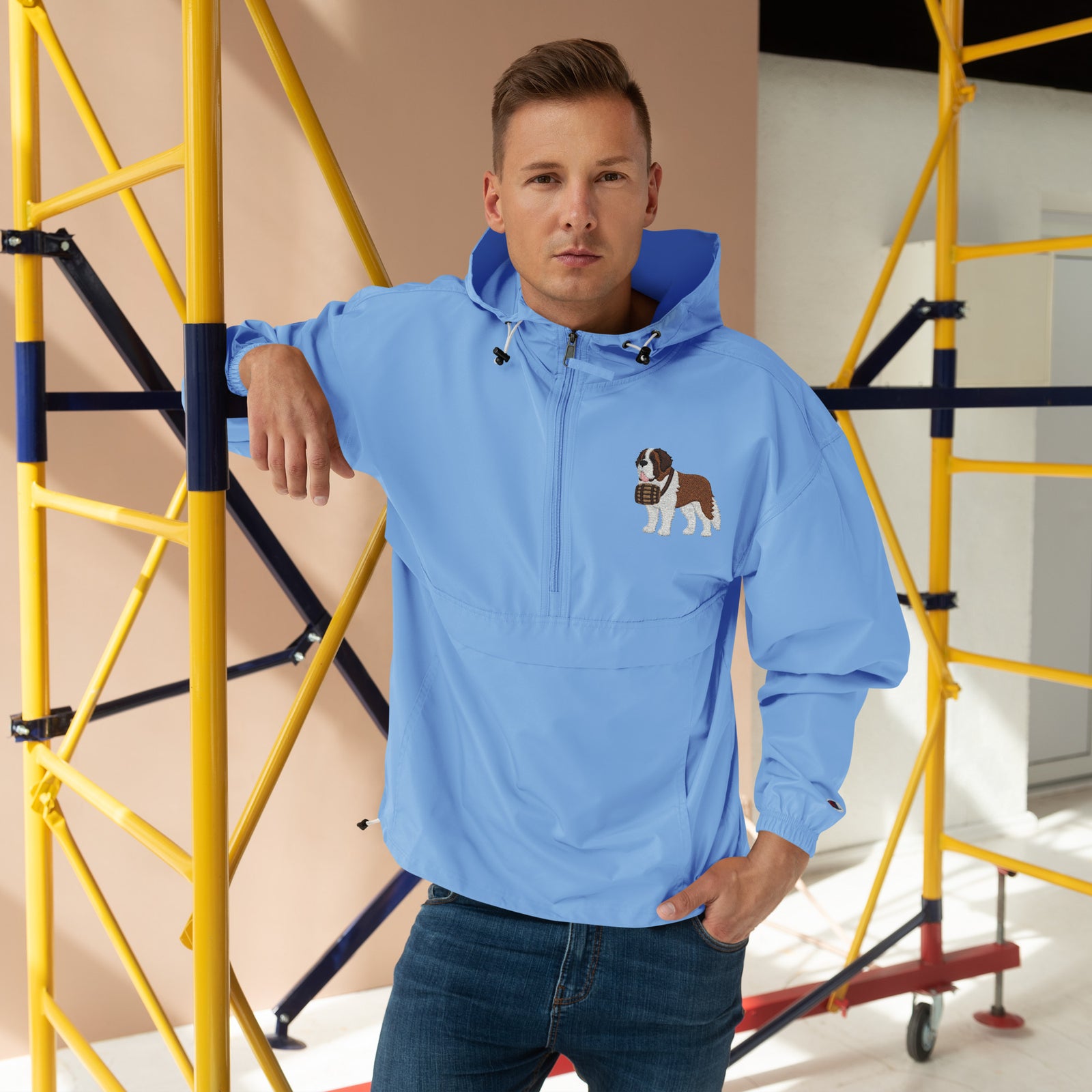 Light blue Champion packable windbreaker with chest embroidered Saint Bernard and barrel, half zip pullover with hood, kangaroo pocket, and zip pouch.
