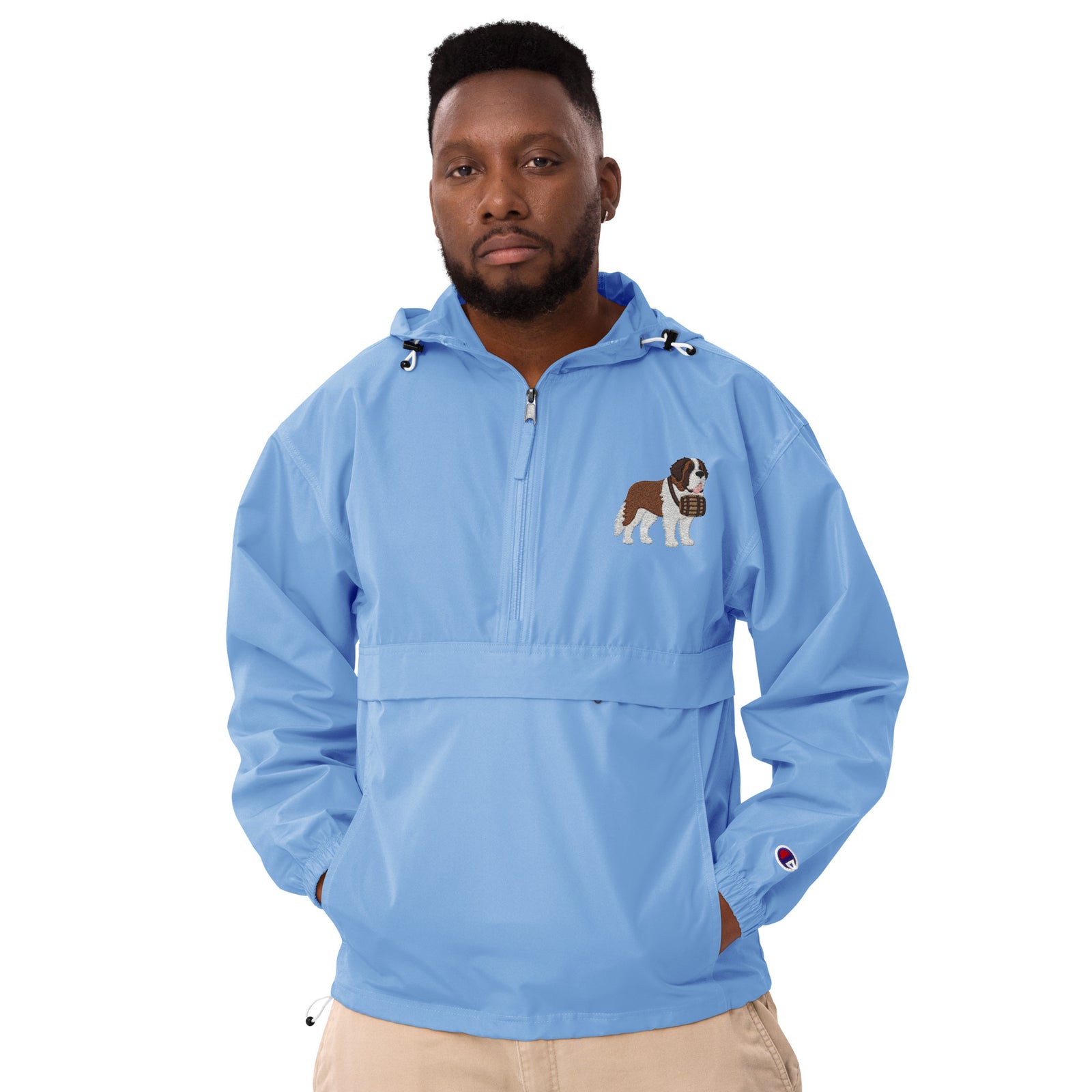 Light blue Champion packable windbreaker with chest embroidered Saint Bernard and barrel, half zip pullover with hood, kangaroo pocket, and zip pouch.