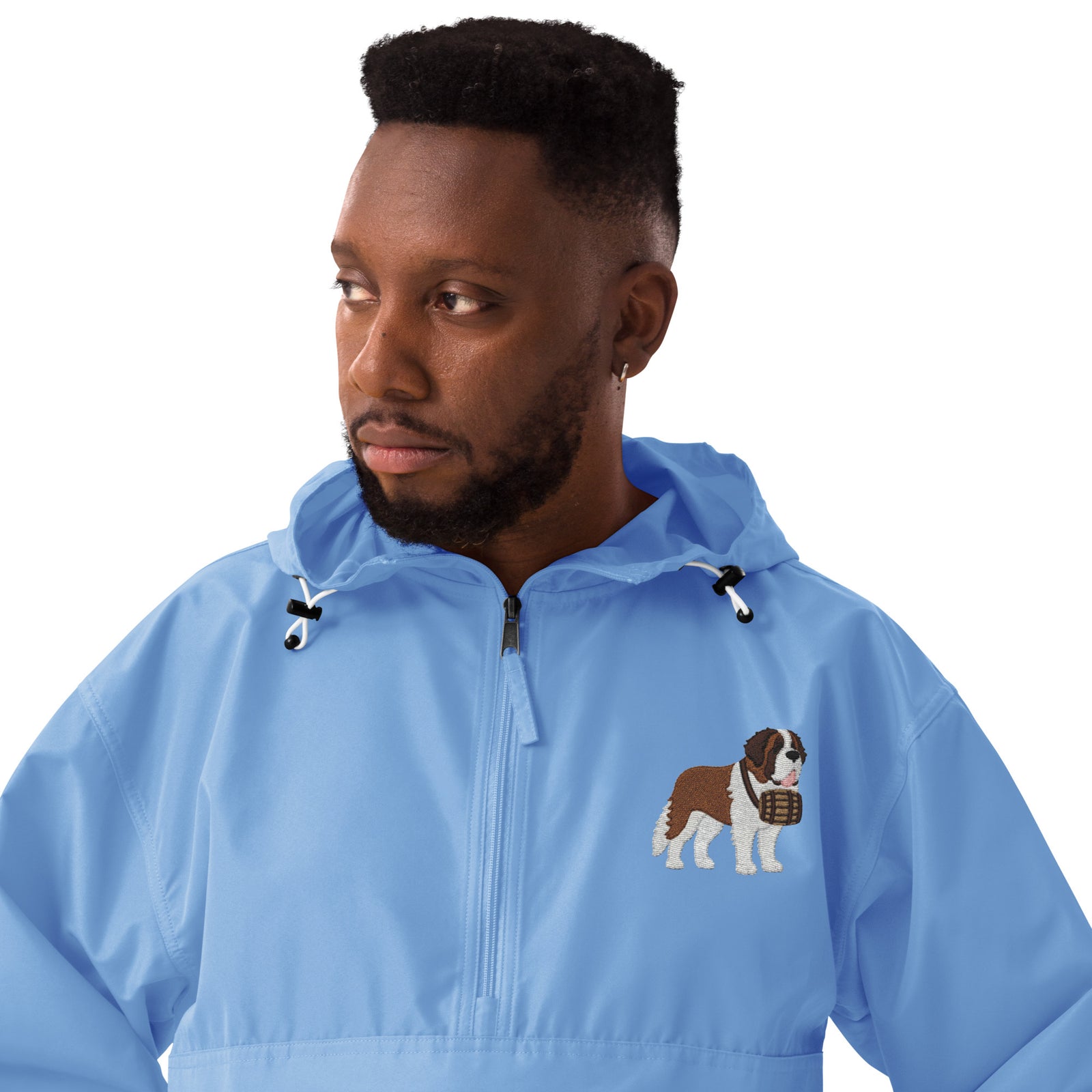 Light blue Champion packable windbreaker with chest embroidered Saint Bernard and barrel, half zip pullover with hood, kangaroo pocket, and zip pouch.