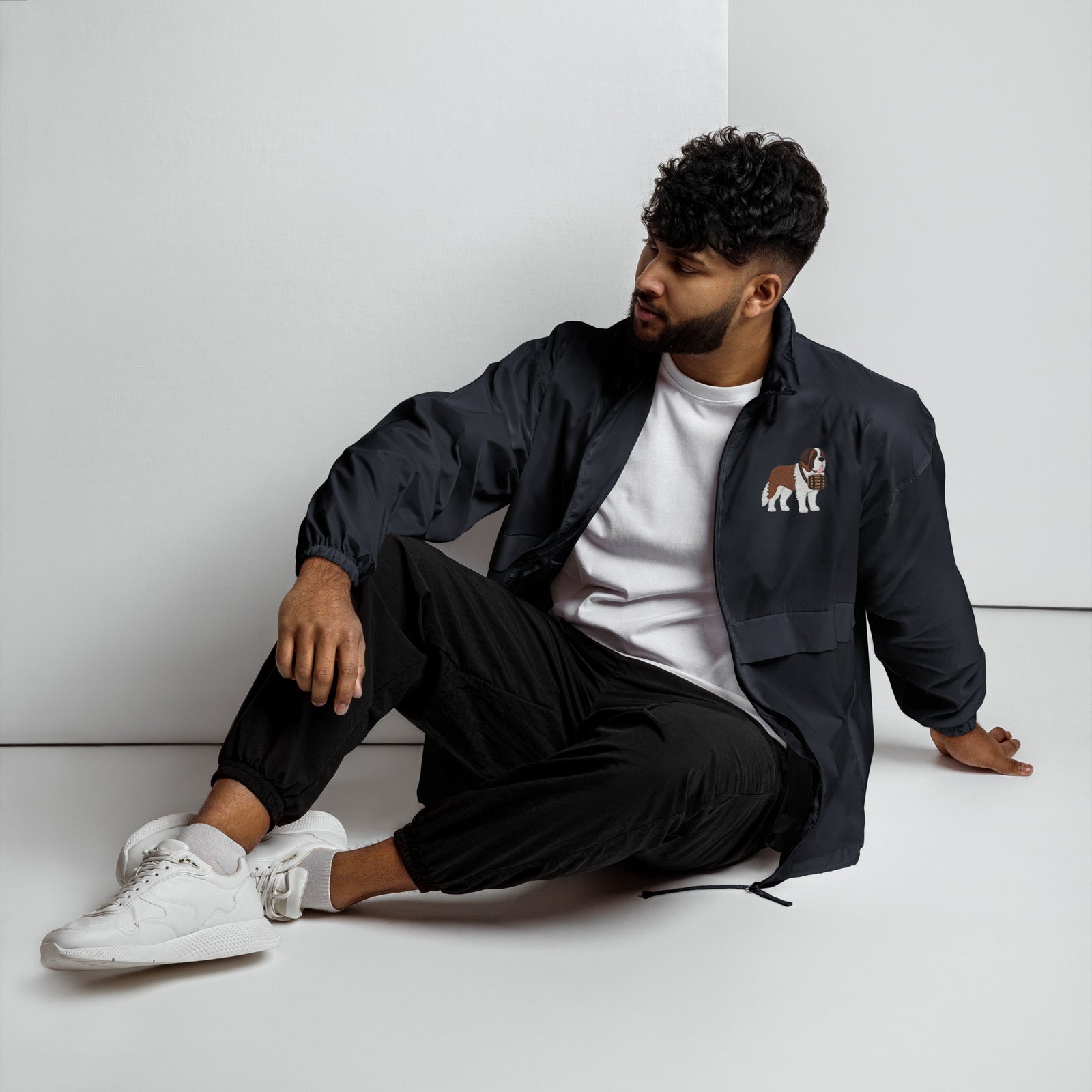 Lightweight, packable navy blue windbreaker with chest embroidered Saint Bernard and barrel, adjustable hood, elastic cuffs, and zip pockets.