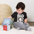 Child wearing a black t-shirt with 'BIG DOG KID' text and a Saint Bernard dog graphic, playing with colorful blocks on a light-colored rug.