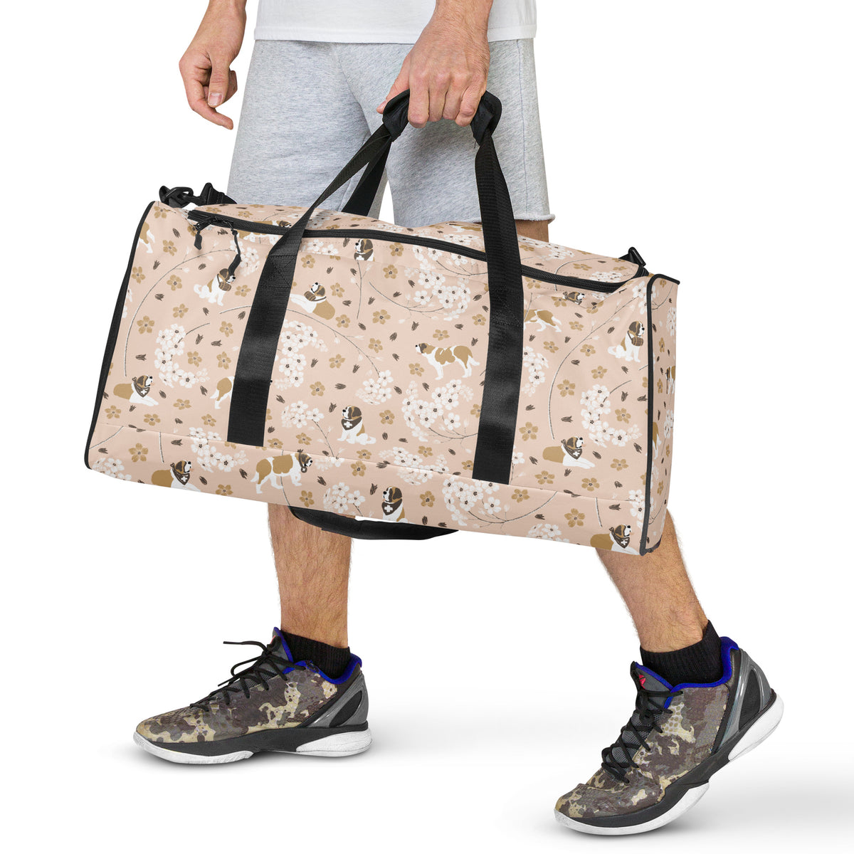 Floral Saint Bernard duffle bag with adjustable padded black shoulder strap, dual carry handles, zippered compartments, and mesh side pocket in white, brown, gold, and soft pink.