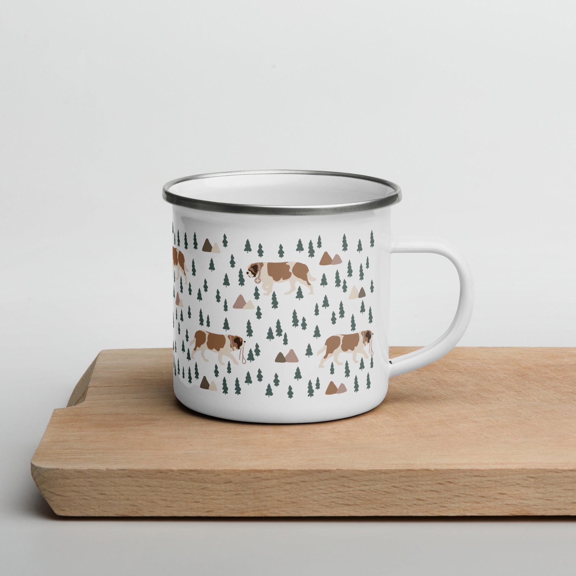 Lightweight 12 oz enamel camp mug. Features a modern pattern of Saint Bernard dogs, mountains and pine trees on a white background by Lucy and Norman