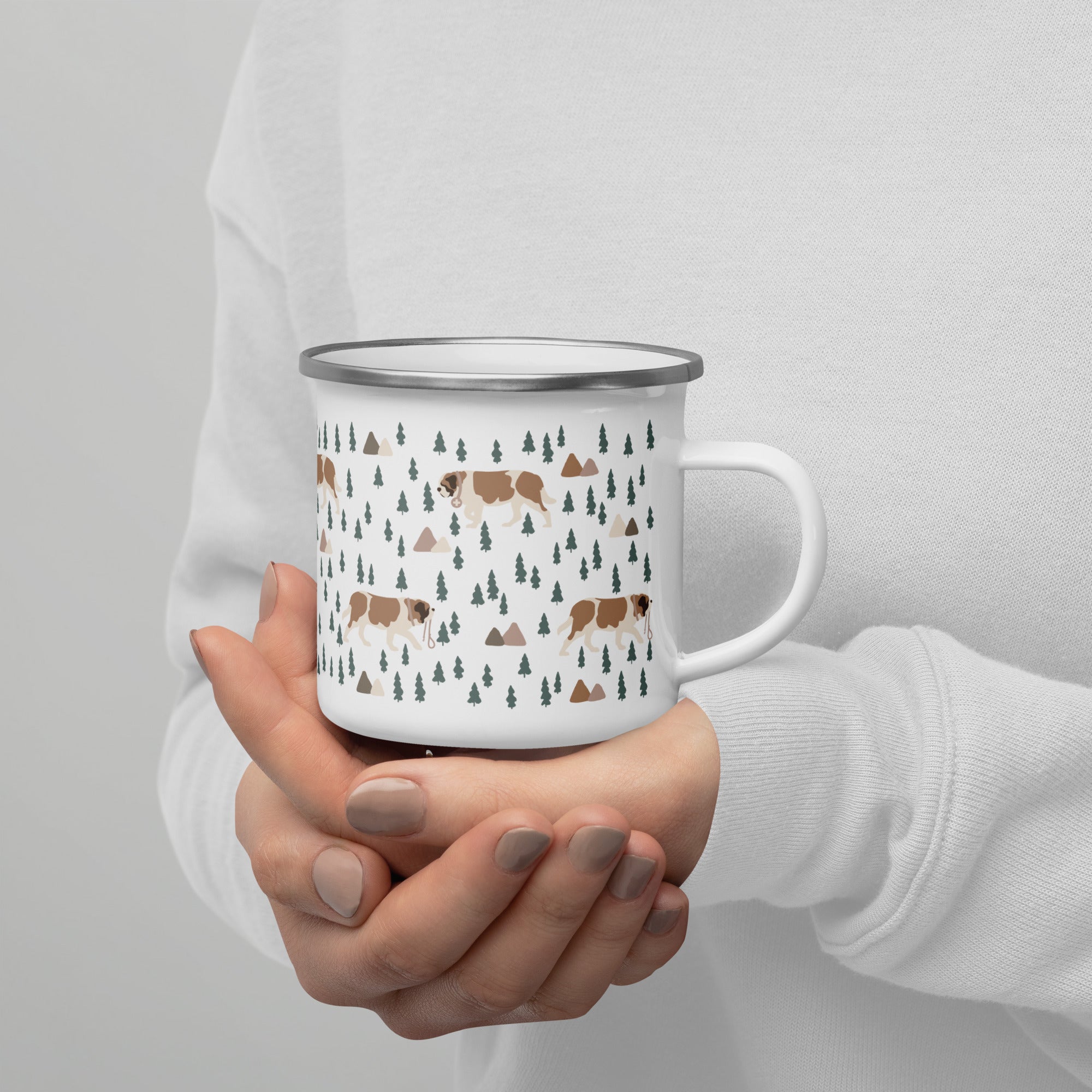 Lightweight 12 oz enamel camp mug. Features a modern pattern of Saint Bernard dogs, mountains and pine trees on a white background by Lucy and Norman