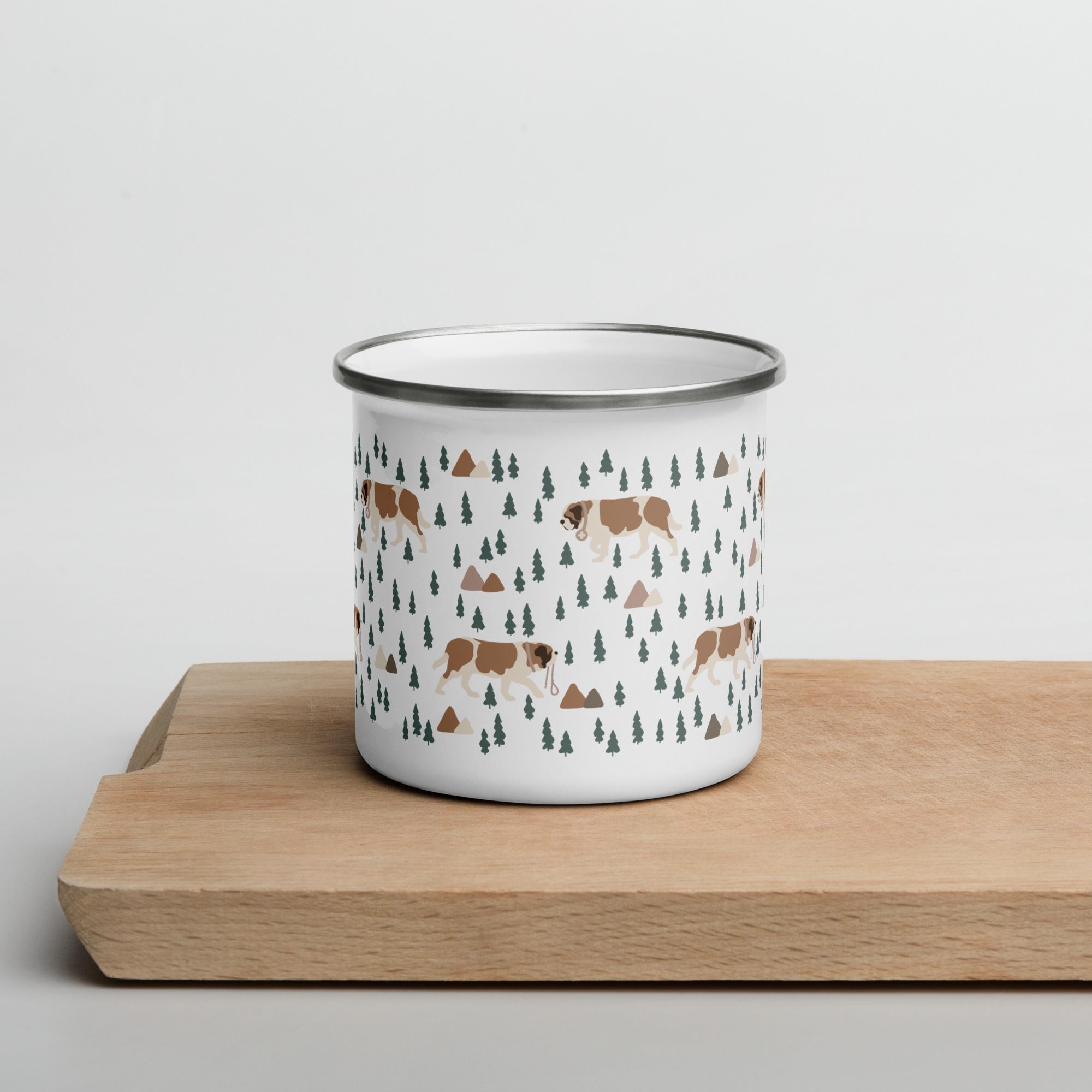 Lightweight 12 oz enamel camp mug. Features a modern pattern of Saint Bernard dogs, mountains and pine trees on a white background by Lucy and Norman