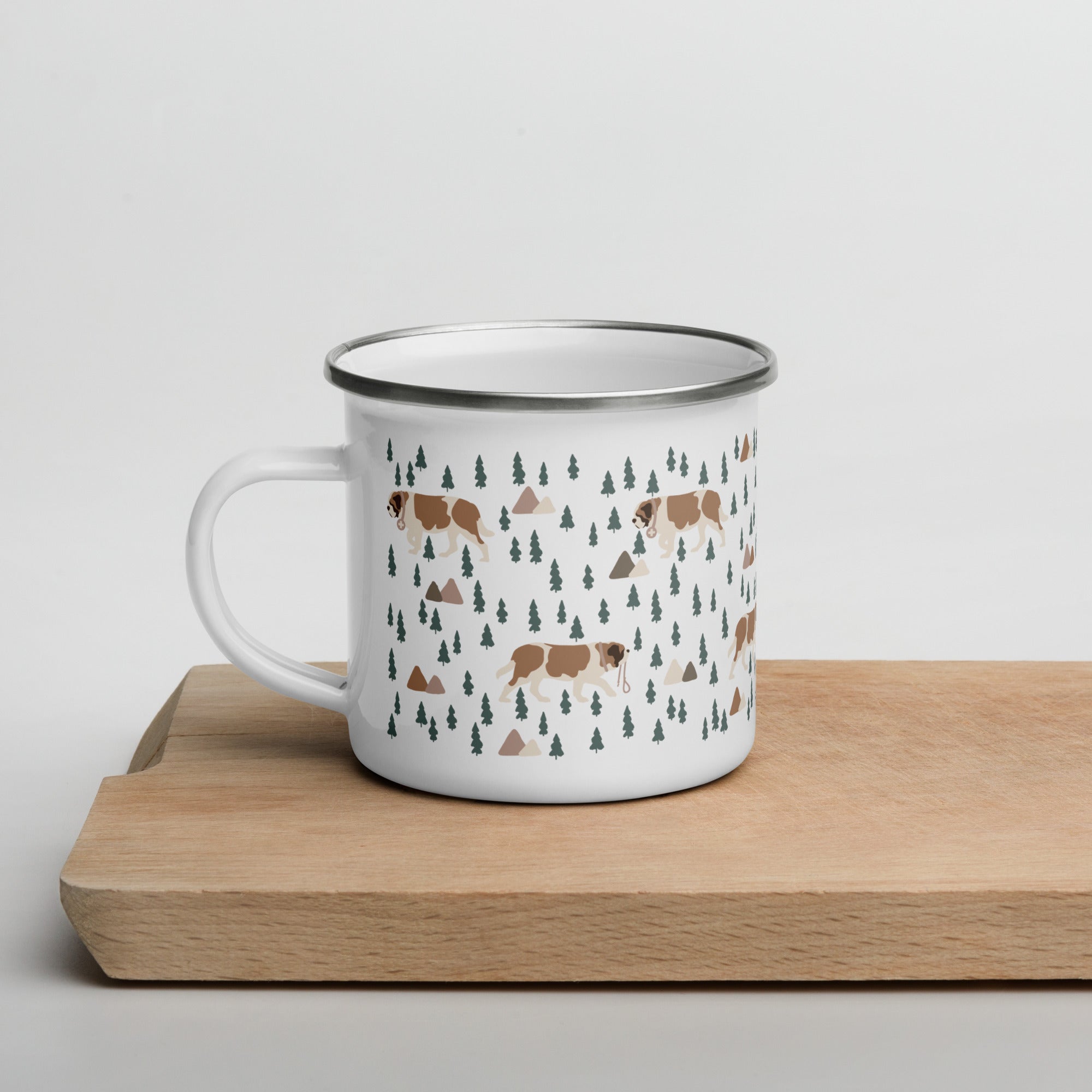 Lightweight 12 oz enamel camp mug. Features a modern pattern of Saint Bernard dogs, mountains and pine trees on a white background by Lucy and Norman