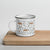 Lightweight 12 oz enamel camp mug. Features a modern pattern of Saint Bernard dogs, mountains and pine trees on a white background by Lucy and Norman