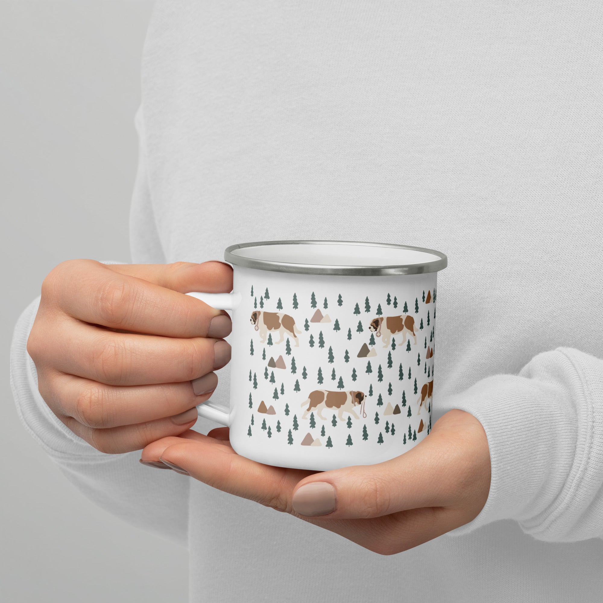 Lightweight 12 oz enamel camp mug. Features a modern pattern of Saint Bernard dogs, mountains and pine trees on a white background by Lucy and Norman