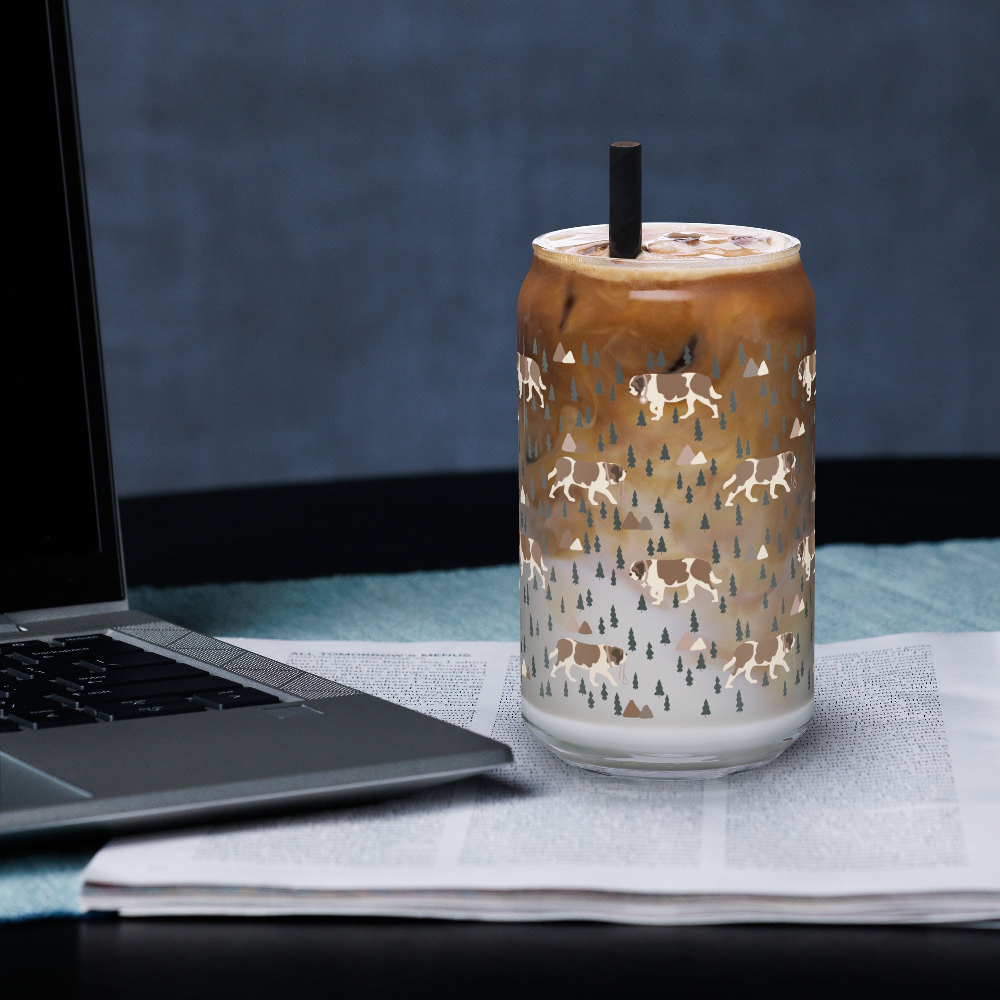 16 oz can-shaped glass tumbler, bamboo wood lid and metal straw. Features a modern pattern of Saint Bernard dogs, mountains and pine trees by Lucy and Norman