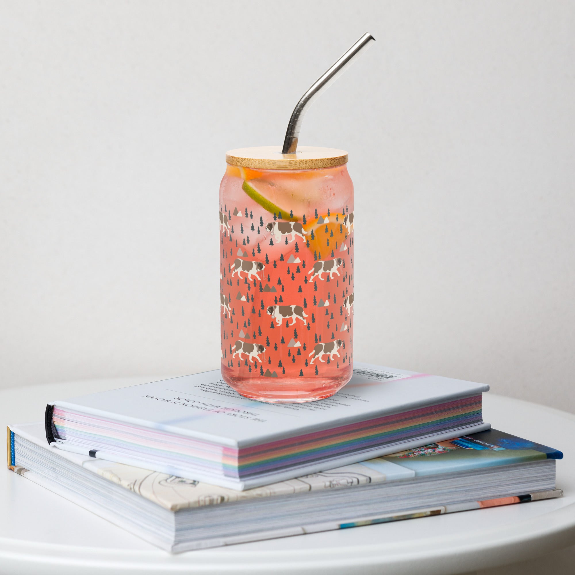 16 oz can-shaped glass tumbler, bamboo wood lid and metal straw. Features a modern pattern of Saint Bernard dogs, mountains and pine trees by Lucy and Norman