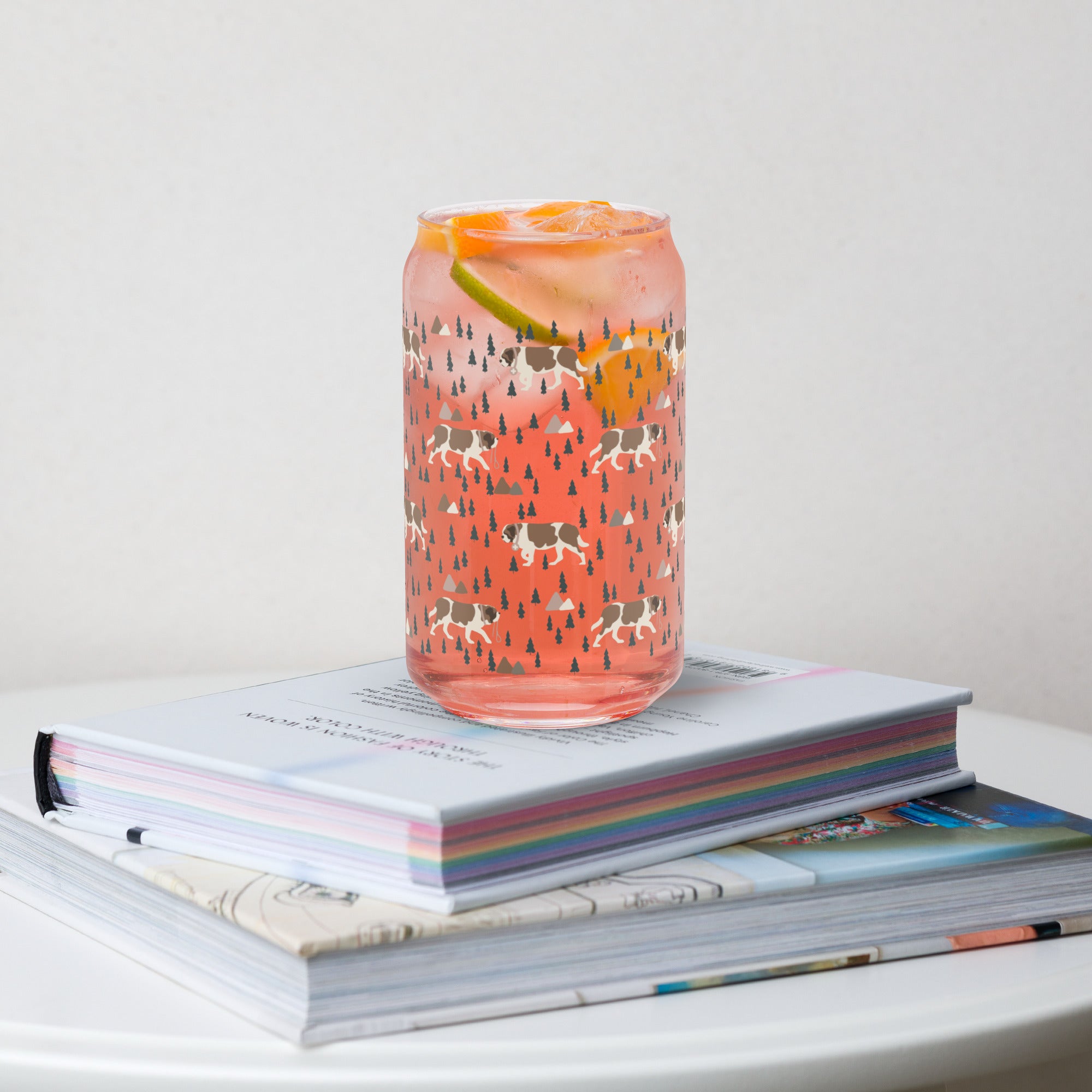 16 oz can-shaped glass tumbler. Features a modern pattern of Saint Bernard dogs, mountains and pine trees by Lucy and Norman