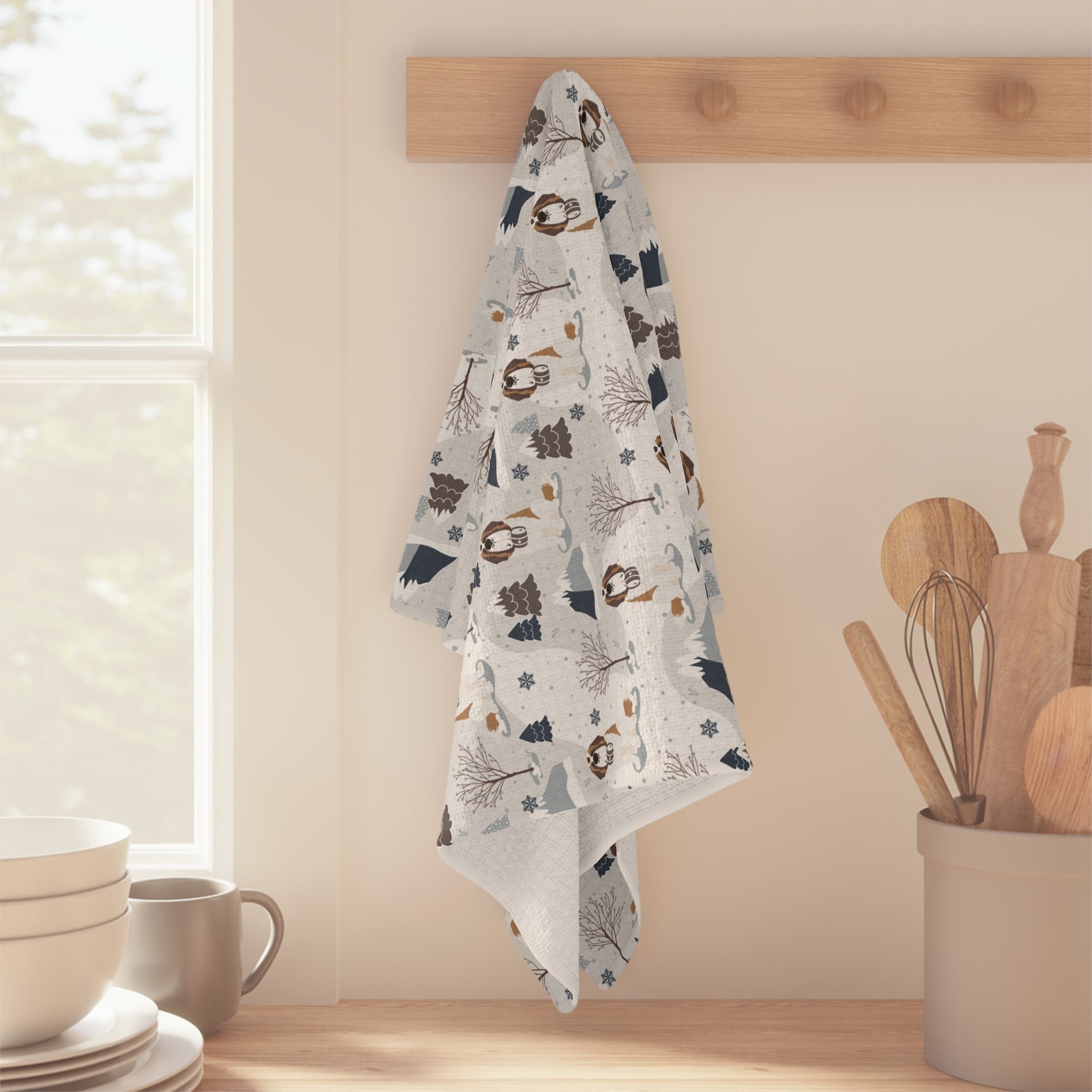 Saint Bernard Alpine microfiber tea towel with a soft gray and white print of Saint Bernards, snowy mountains, and pine trees, hanging over a kitchen counter.