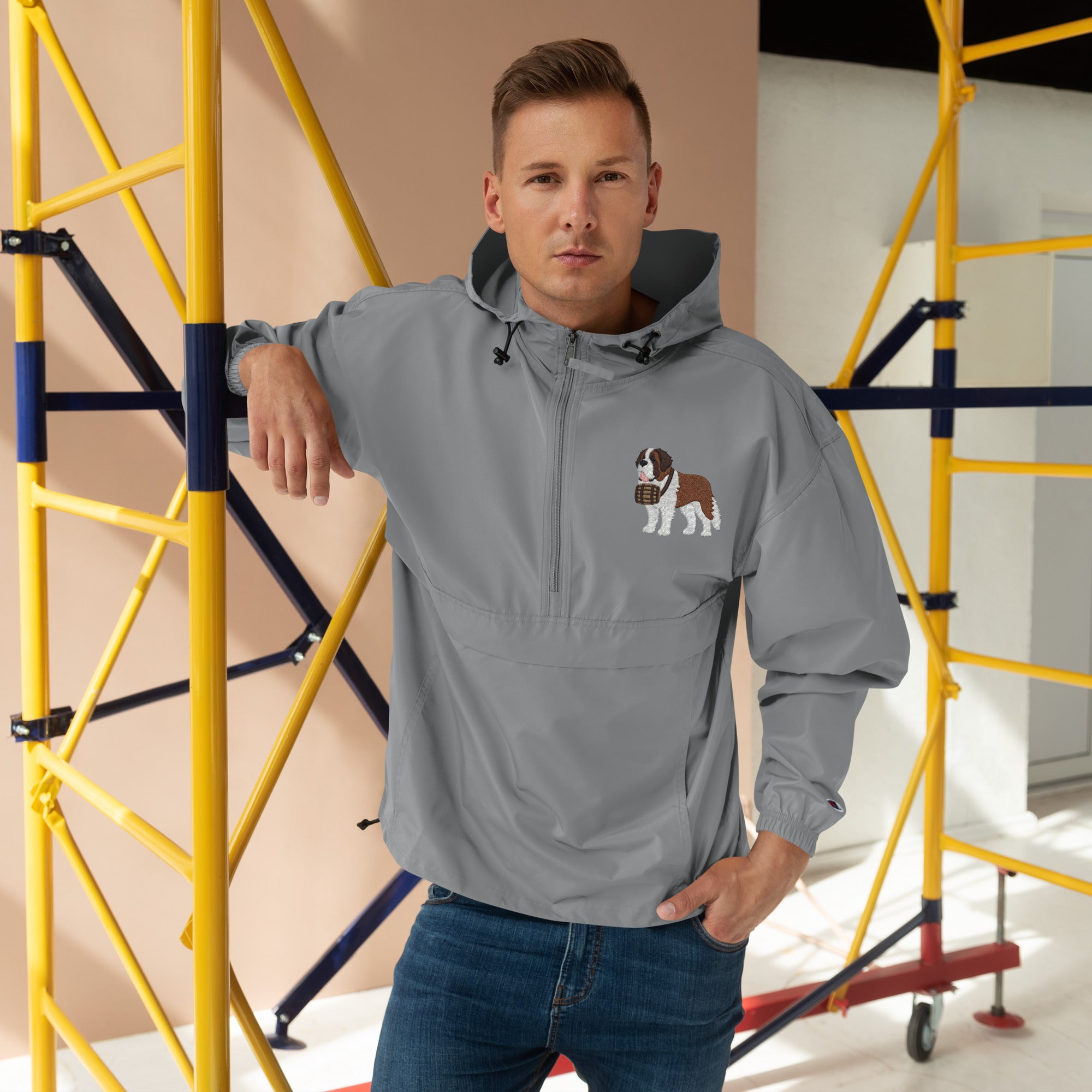 Light gray Champion packable windbreaker with chest embroidered Saint Bernard and barrel, half zip pullover with hood, kangaroo pocket, and zip pouch.