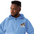 Light blue Champion packable windbreaker with chest embroidered Saint Bernard and barrel, half zip pullover with hood, kangaroo pocket, and zip pouch.