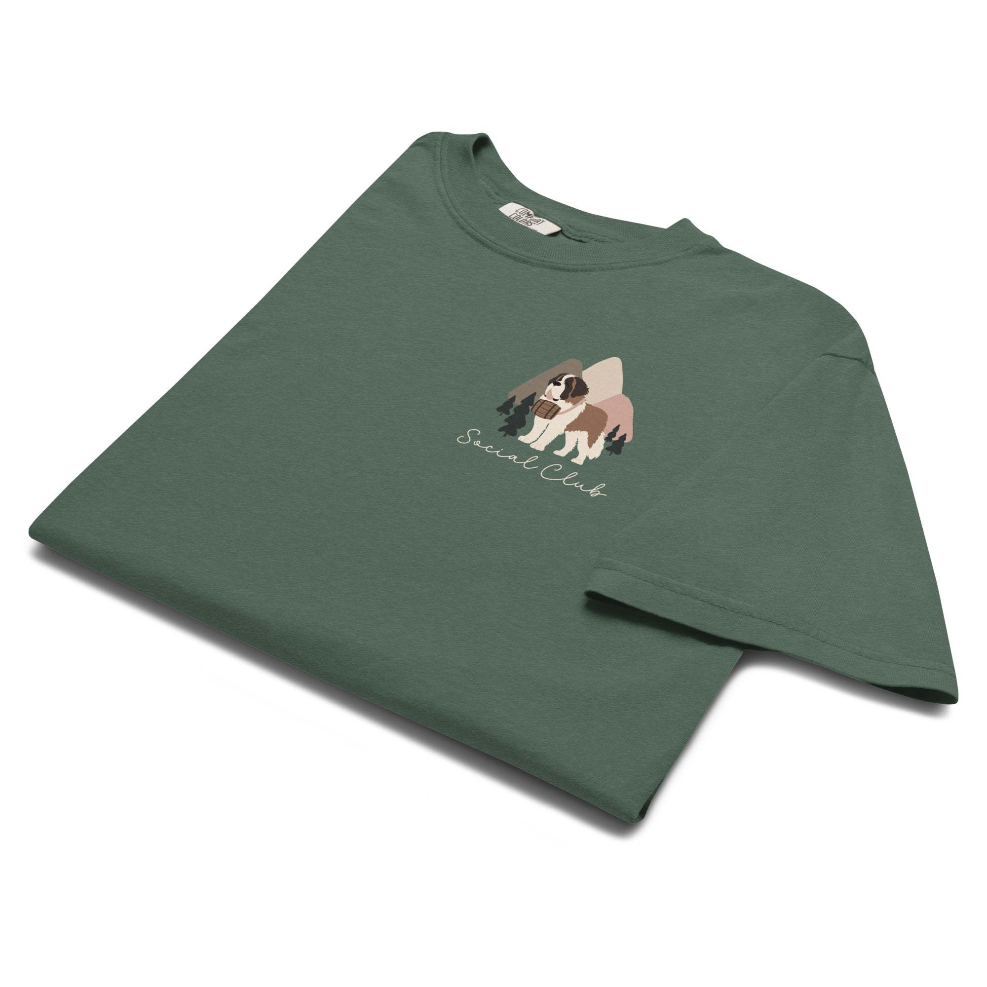 Comfort Colors blue spruce t-shirt featuring a woodland-mountain theme with Saint Bernard dogs on the back with a badge on left chest. Perfect Saint Bernard gift for dog lovers.