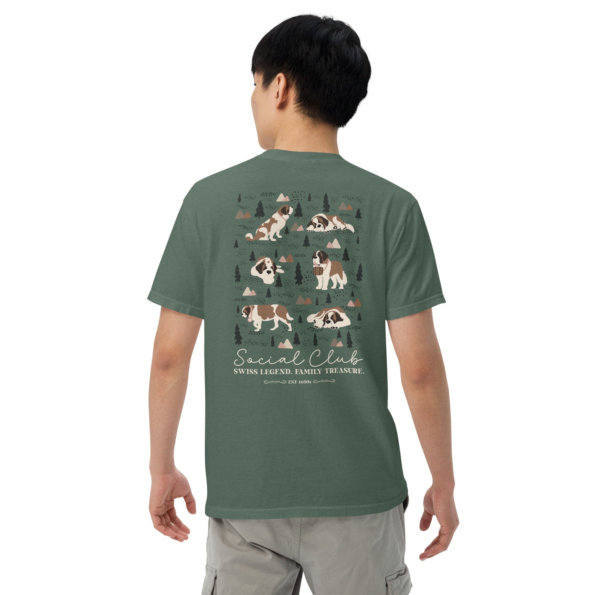 Comfort Colors blue spruce t-shirt featuring a woodland-mountain theme with Saint Bernard dogs on the back with a badge on left chest. Perfect Saint Bernard gift for dog lovers.