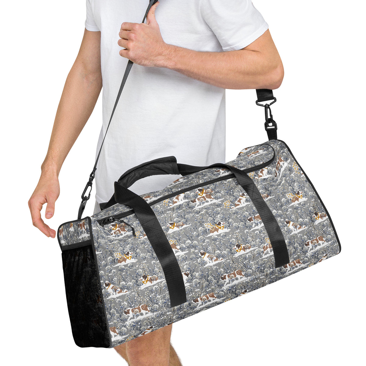 Snowflowers Saint Bernard floral duffle bag in soft gray, blue, white, and winter floral tones with padded black shoulder strap, handles, zip compartment, and mesh side pocket.