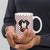 White ceramic mug featuring a cute illustrated Saint Bernard dog wearing a rescue barrel, surrounded by a red Swiss cross pattern. Perfect gift for St Bernard dog lovers and Swiss Alps fans by Lucy and Norman.