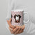 White ceramic mug featuring a cute illustrated Saint Bernard dog wearing a rescue barrel, surrounded by a red Swiss cross pattern. Perfect gift for St Bernard dog lovers and Swiss Alps fans by Lucy and Norman.
