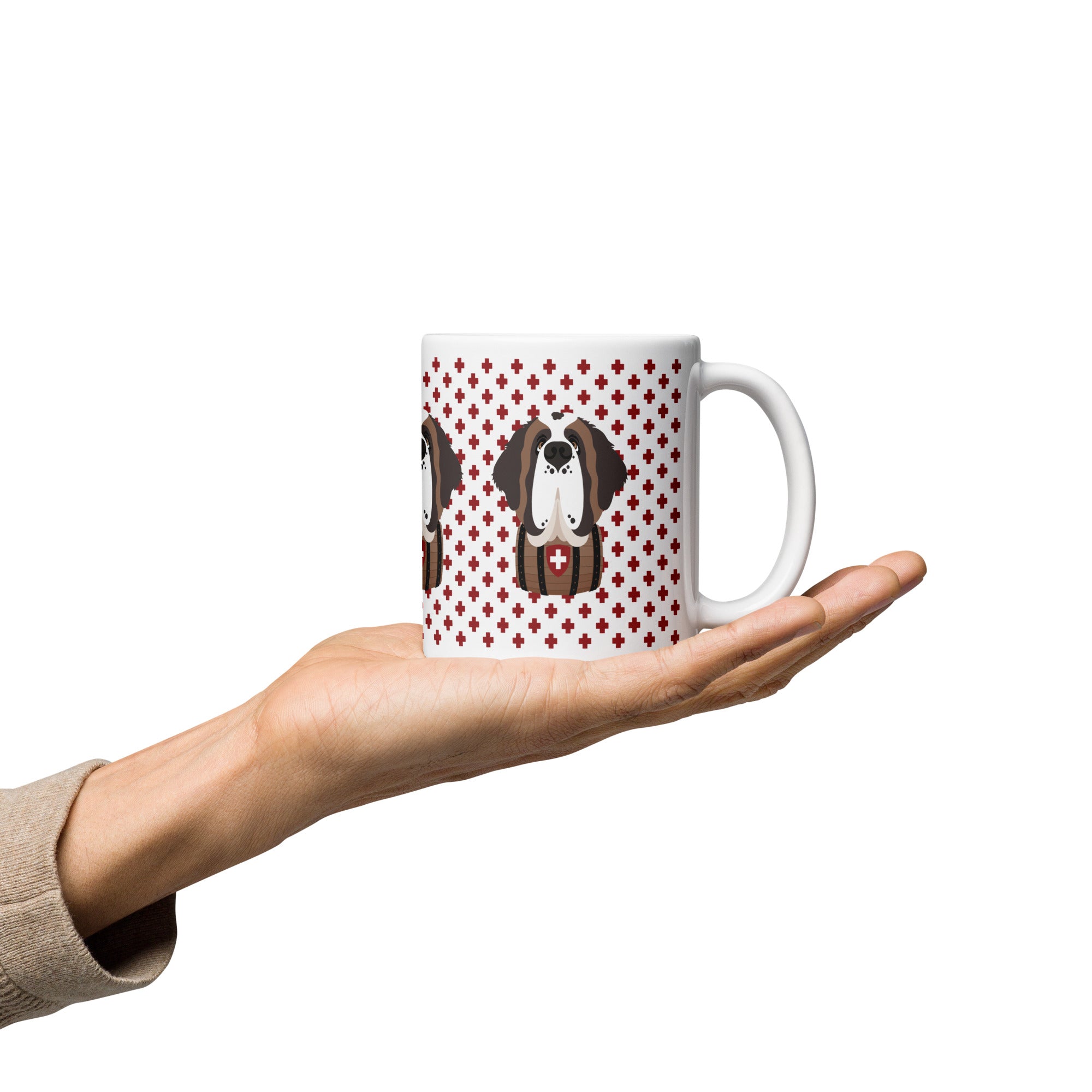 White ceramic 11 ounce mug featuring a cute illustrated Saint Bernard dog wearing a rescue barrel, surrounded by a red Swiss cross pattern. Perfect gift for St Bernard dog lovers and Swiss Alps fans by Lucy and Norman.