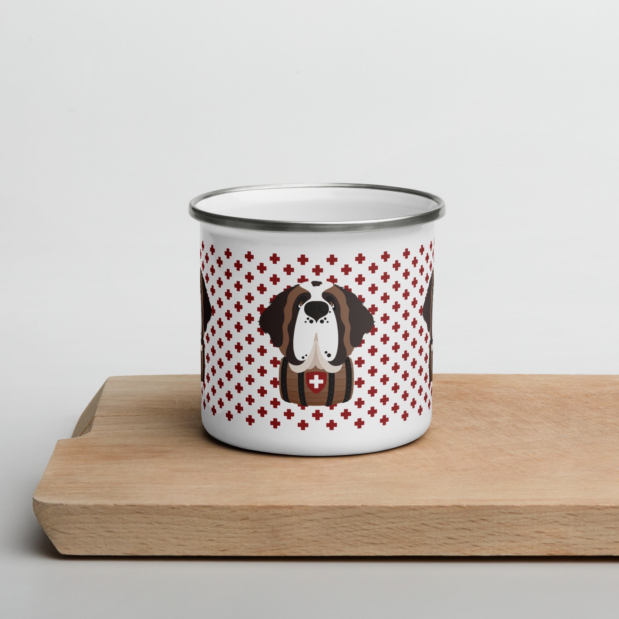 White enamel 12 ounce camp mug with silver rim featuring a cute illustrated Saint Bernard dog wearing a rescue barrel, surrounded by a red Swiss cross pattern. Perfect gift for St Bernard dog lovers and Swiss Alps fans by Lucy and Norman.