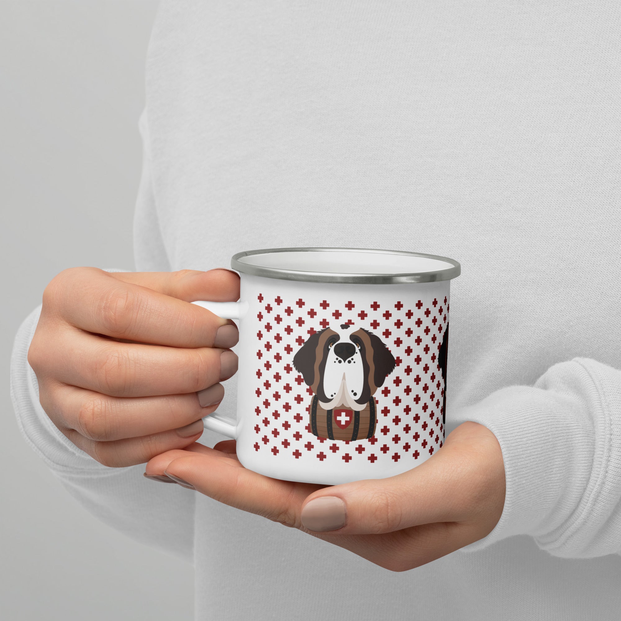 White enamel 12 ounce camp mug with silver rim featuring a cute illustrated Saint Bernard dog wearing a rescue barrel, surrounded by a red Swiss cross pattern. Perfect gift for St Bernard dog lovers and Swiss Alps fans by Lucy and Norman.