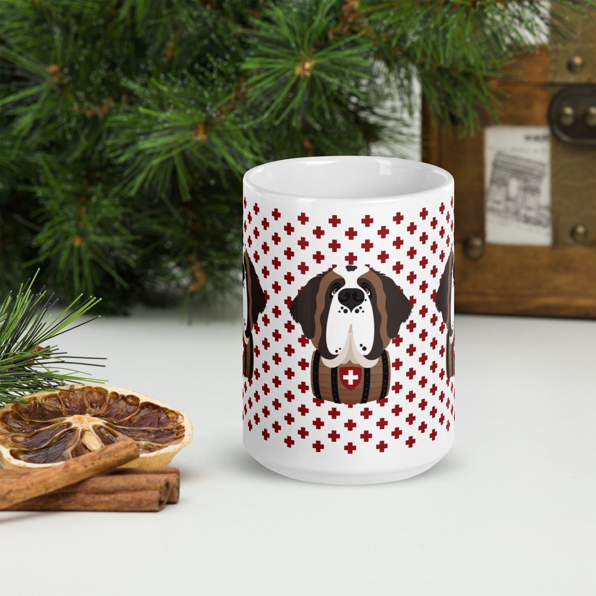 White ceramic 15 ounce mug featuring a cute illustrated Saint Bernard dog wearing a rescue barrel, surrounded by a red Swiss cross pattern. Perfect gift for St Bernard dog lovers and Swiss Alps fans by Lucy and Norman.
