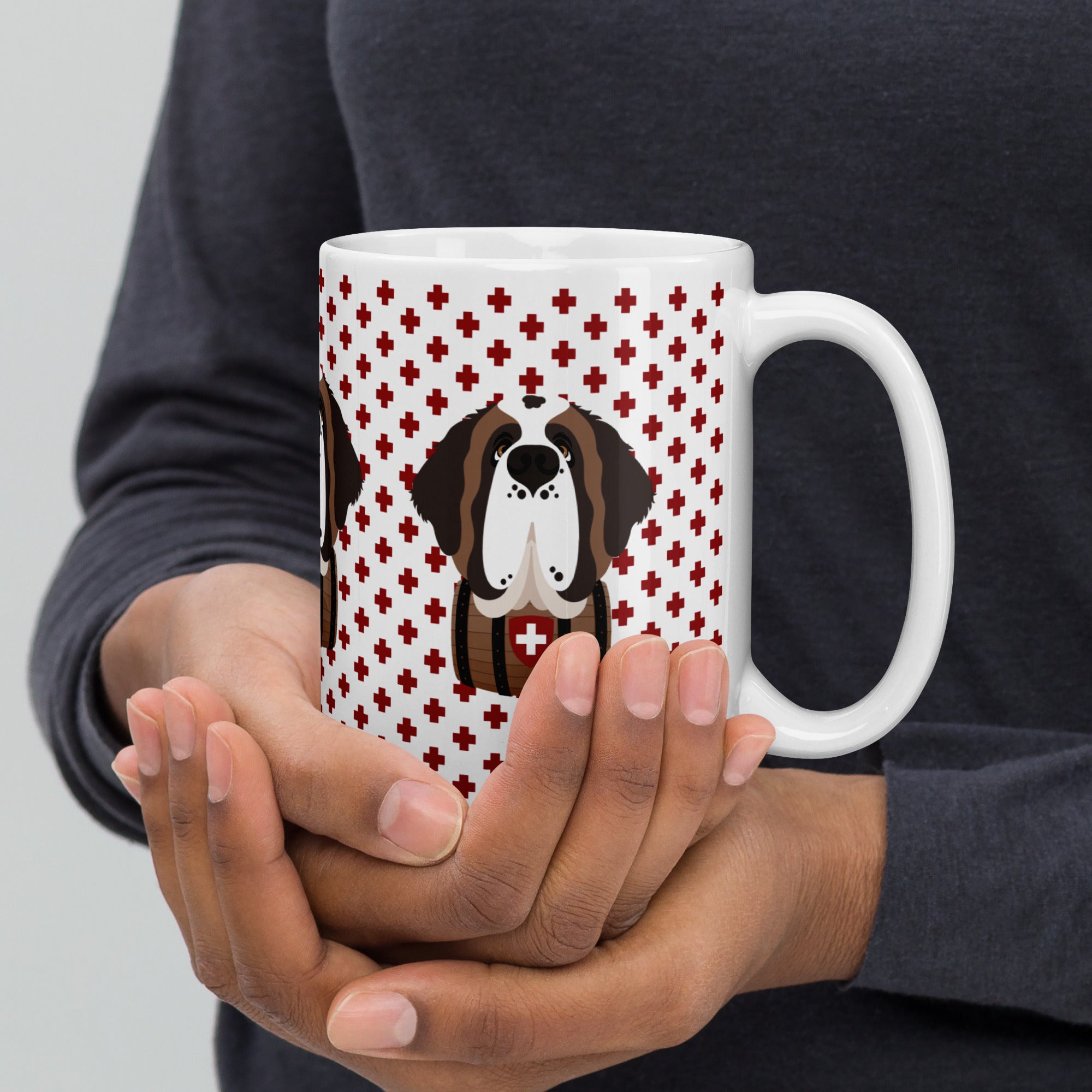 White ceramic 15 ounce mug featuring a cute illustrated Saint Bernard dog wearing a rescue barrel, surrounded by a red Swiss cross pattern. Perfect gift for St Bernard dog lovers and Swiss Alps fans by Lucy and Norman.